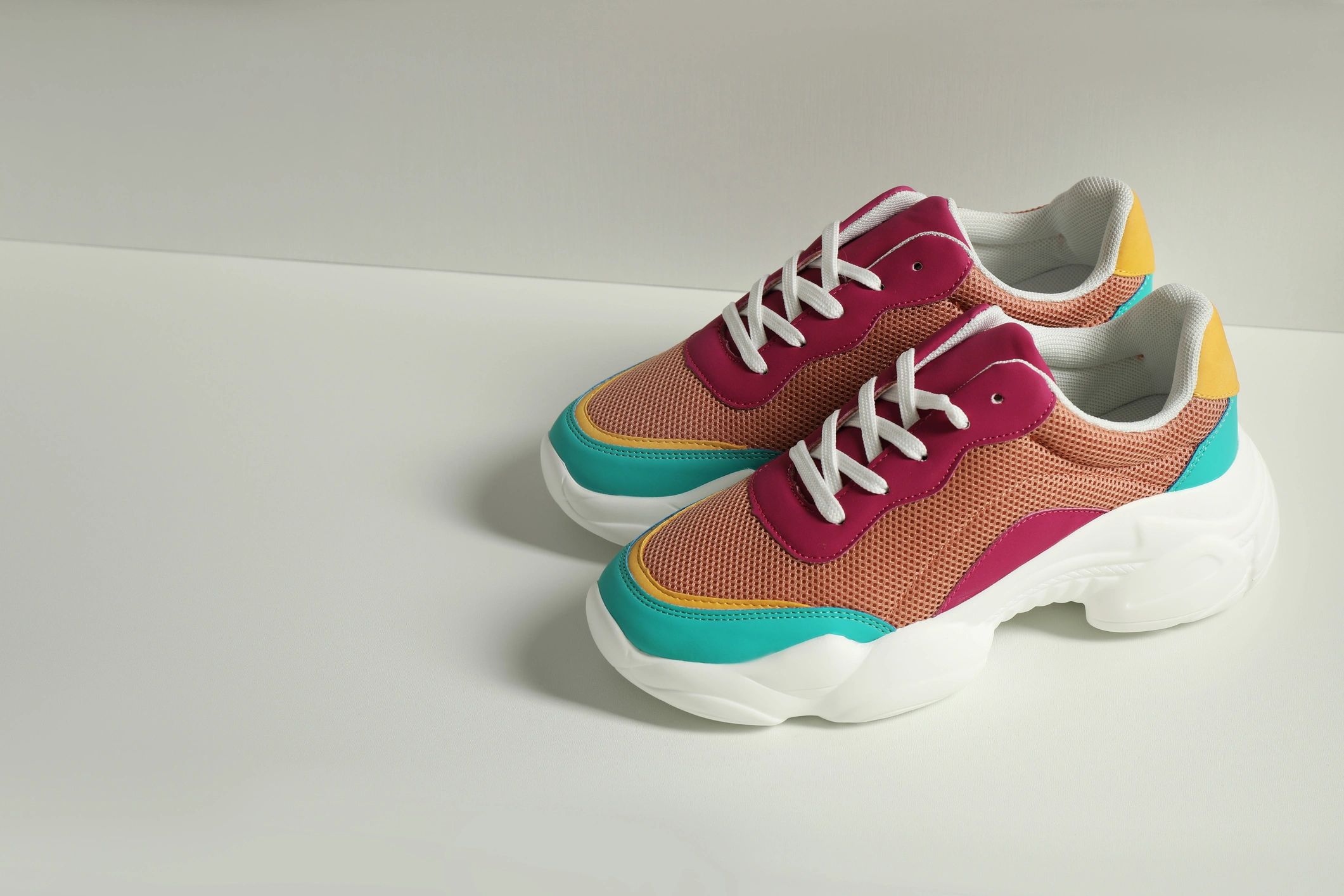 Multi-colored sneakers are stacked in a pile on